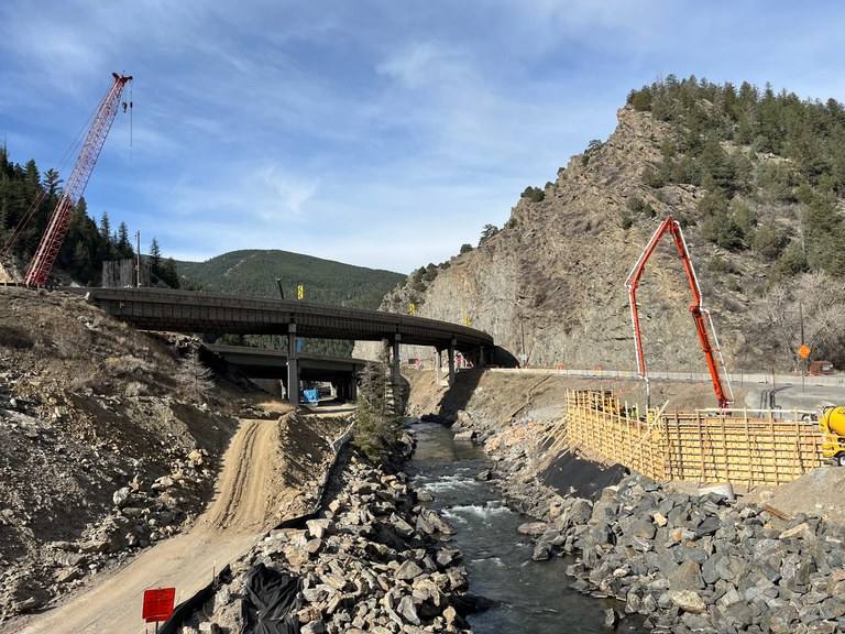 An I-70 bridge over Clear Creek at Floyd Hill with construction under way on both banks, in a CDOT photograph dated March 30, 2026. Sunday night's eastbound closure shifts traffic onto the newly completed bridge over the creek.