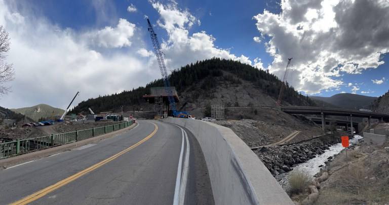I-70 Floyd Hill construction in a Colorado Department of Transportation photograph from March 2026, with cranes and a new bridge pier above Clear Creek. Overnight closures on Oct. 18, 19 and 20 advance the segmental bridge and a new eastbound alignment.