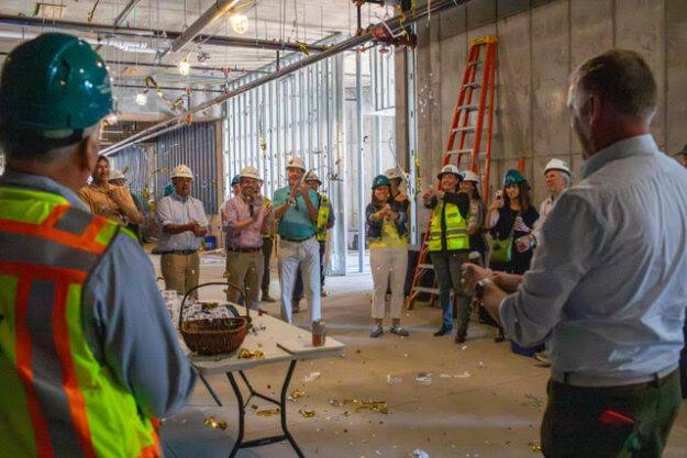 Confetti flies as crews and officials celebrate the topping out of Building A at Timber Ridge Village.