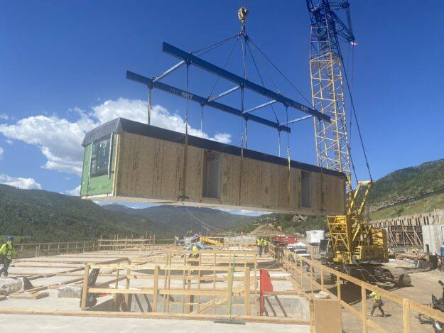A modular home is craned into place at the Timber Ridge Village redevelopment on June 30, 2025.