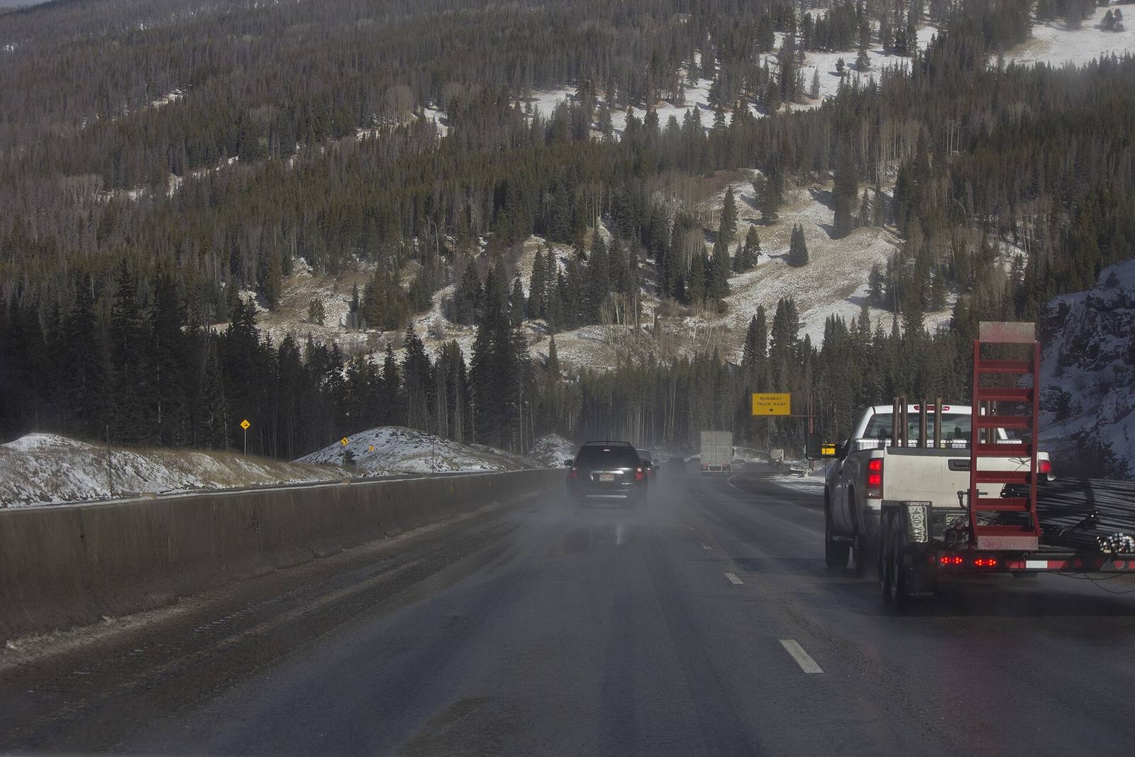 Westbound traffic on Interstate 70 at Vail Pass in a file photograph, with snow dusting the forest above a wet road and a runaway truck ramp sign ahead. The pass sat inside this week's winter weather advisory, which covered terrain above 9,500 feet.